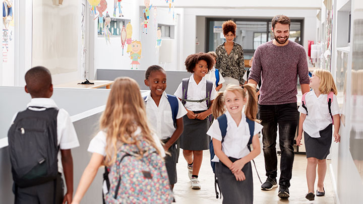 Teacher and pupils walking along a corridor in a busy elementary school